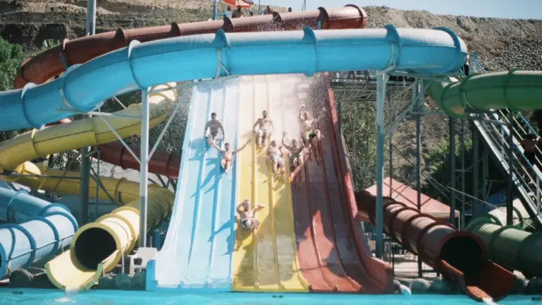 Toboggans aquatiques colorés au bord d'une piscine extérieure pour une journée estivale.