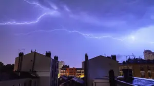 Foudre frappant le ciel au-dessus des immeubles parisiens lors d'un orage nocturne intense.