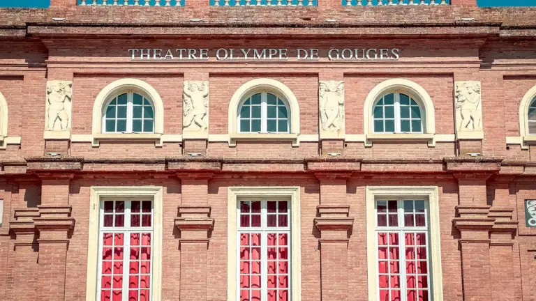Façade architecturale historique du Théâtre Olympe de Gouges avec briques rouges et fenêtres.