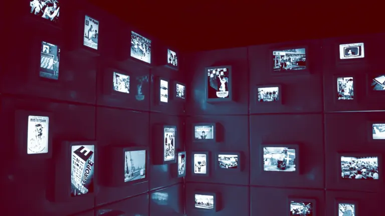 Mur sombre parsemé de nombreux petits écrans diffusant des œuvres d'art numériques.