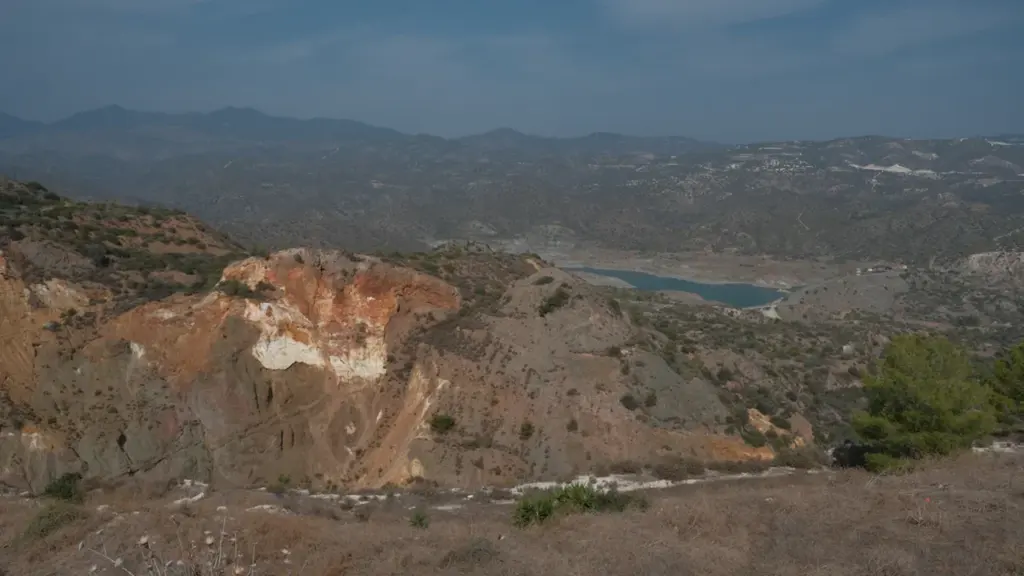Paysage aride et rocailleux avec un plan d'eau asséché sous un ciel bleu.