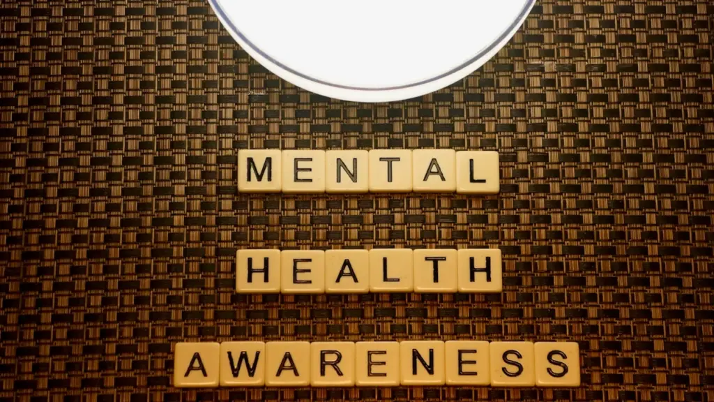 Des lettres de jeu formant les mots Mental Health Awareness sur fond texturé sombre.