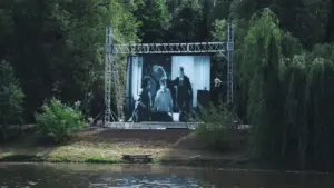 Un grand écran de cinéma installé en plein air dans un parc arboré.