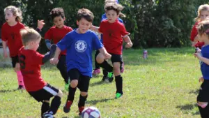 Groupe d'enfants pratiquant le football sur un terrain herbeux lors de la rentrée.