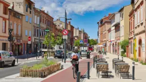 Une rue urbaine apaisée avec cycliste, larges trottoirs et aménagement végétalisé à Toulouse.