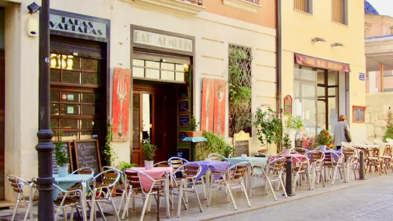 Terrasse d'un restaurant avec des tables et chaises disposées sur une place pavée.