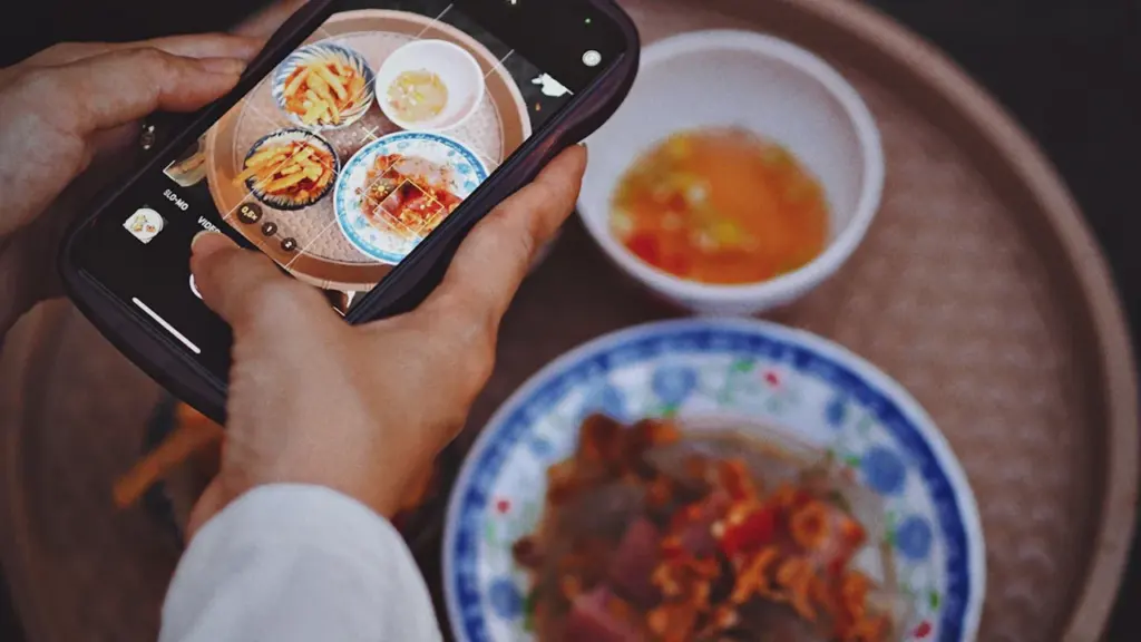 Gros plan sur des mains photographiant un plat avec un smartphone de manière artistique.