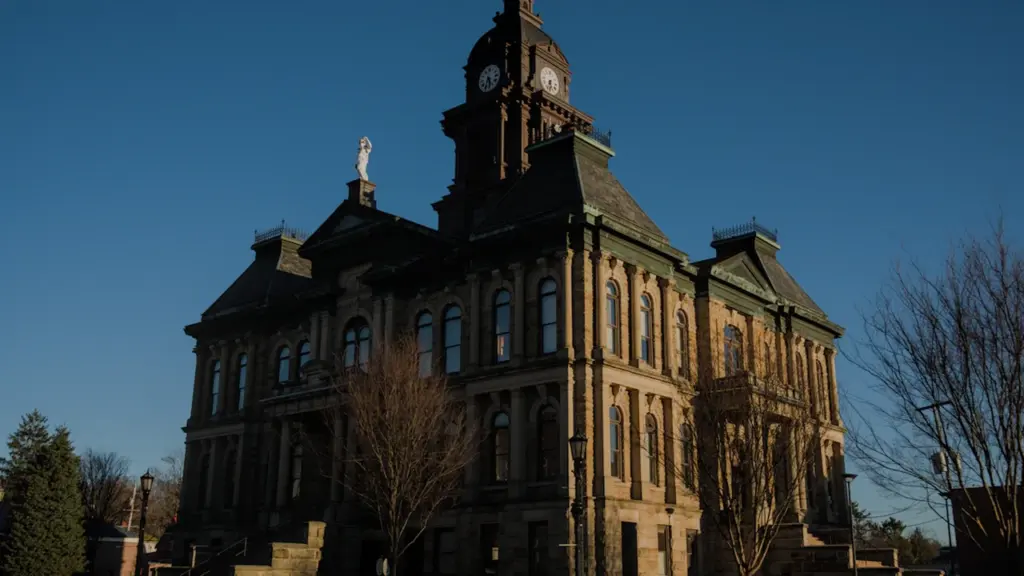 Façade architecturale historique d'un bâtiment administratif avec une tour horloge sous un ciel bleu.