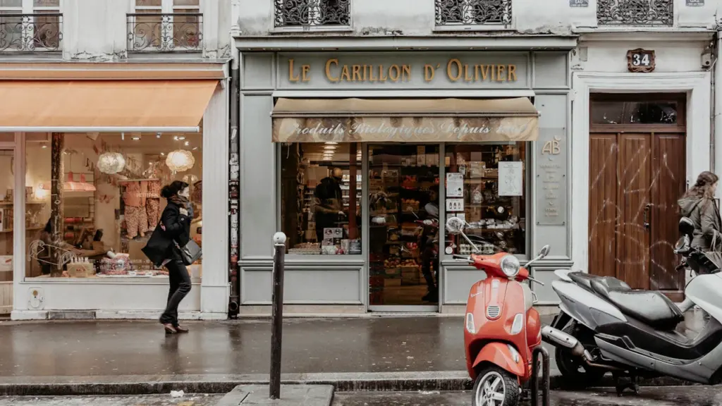 Une devanture de magasin classique dans une rue commerçante avec un scooter garé.