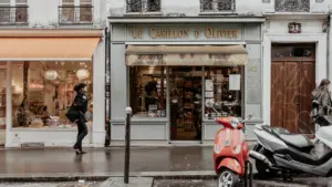 Une devanture de magasin classique dans une rue commerçante avec un scooter garé.