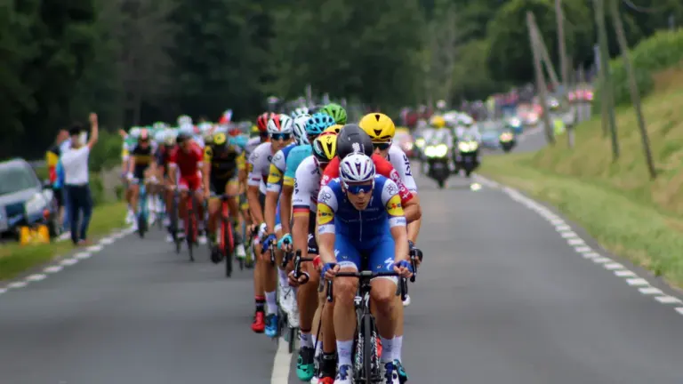 Un peloton de cyclistes professionnels en pleine course sur une route de campagne française.